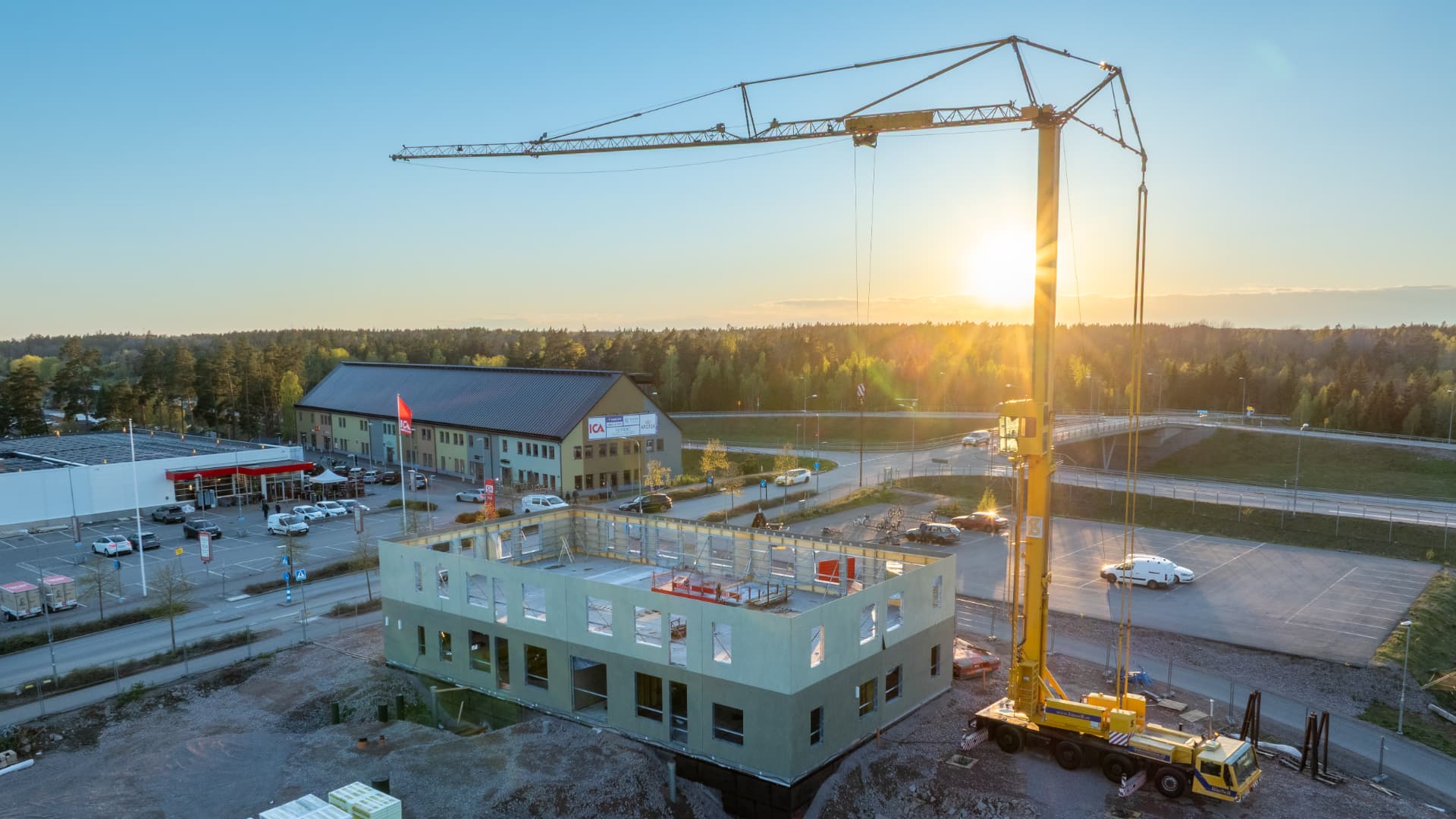 Husväggar och byggkran i kvällsljus i maj 2026